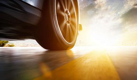 日落时汽车快速行驶的低角度侧面视图，具有运动速度效果.