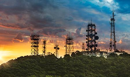 天线塔和通信中继器的剪影，在日落的背景下与山通信.